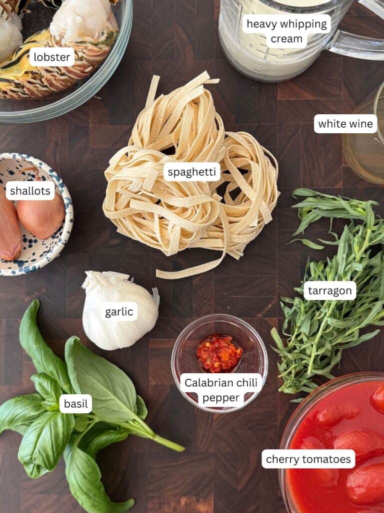 Ingredients for creamy lobster pasta. They include lobster tails, pasta, heavy cream, shallots, garlic, chilies, basil, tarragon, tomatoes, and white wine.