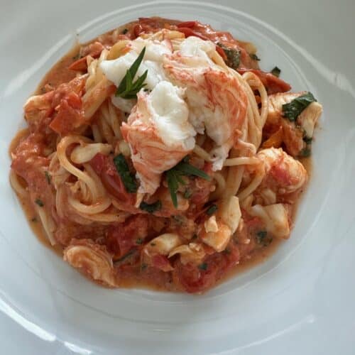Creamy lobster pasta in a white plate.