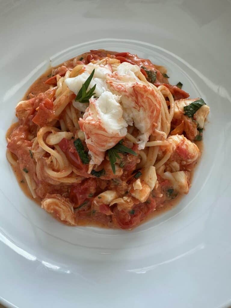 Creamy lobster pasta in a white plate.